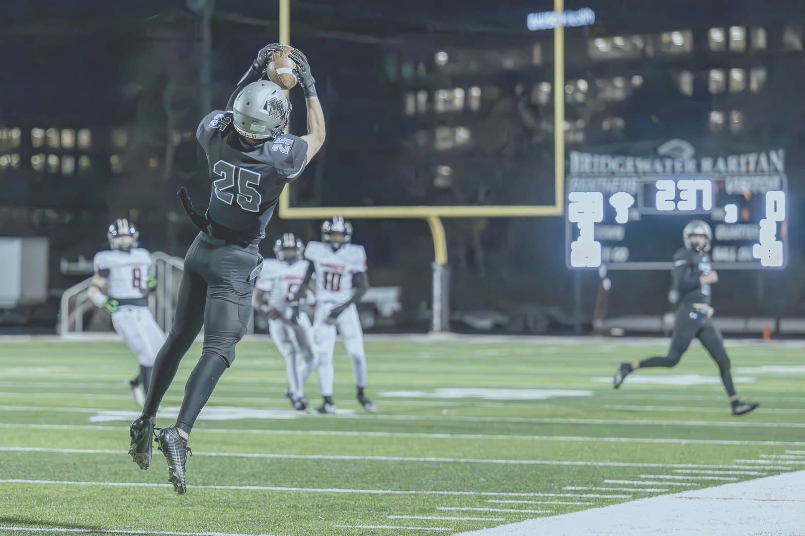 BRHS #25 makes a catch at night with scoreboard in frame