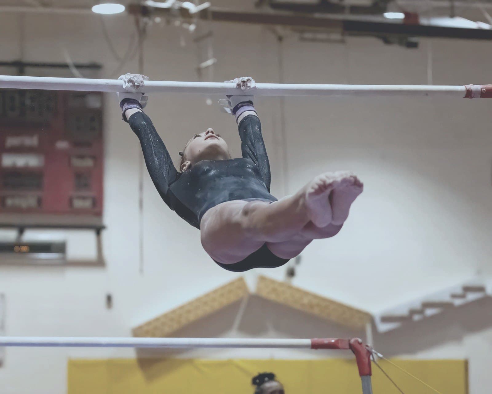 Gymnast swings on the high bar, feet tucked